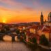 Vista panorámica de una ciudad histórica europea al atardecer con un río, puente y catedral
