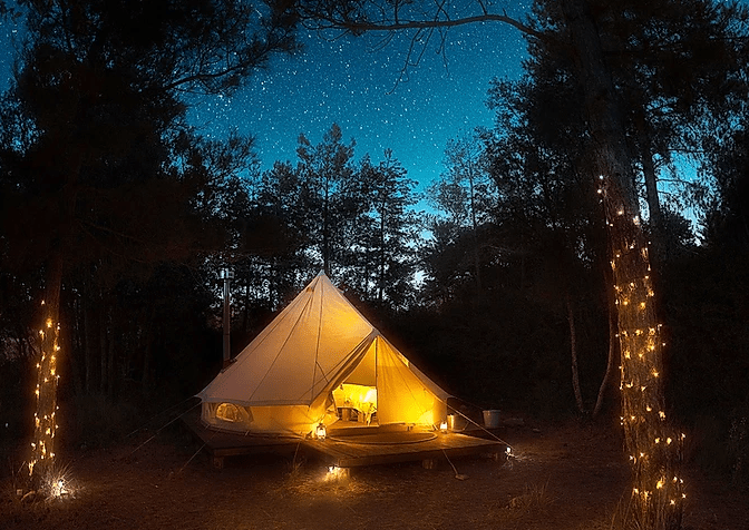 Tienda del glamping Forest Days de Lleida al anochecer iluminada y rodeada de vegetación